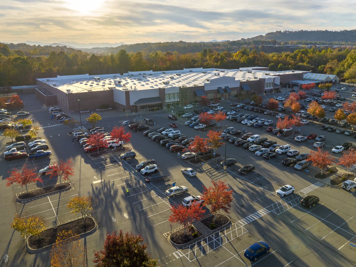 Fachmarktzentrum mit großem Parkplatz aus der Luft im Abendlicht